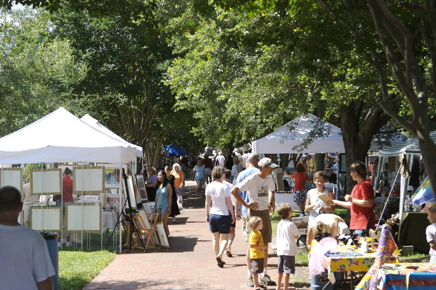 Shoppers browse artists' tents under the oaks at Palafox Market in downtown Pensacola.