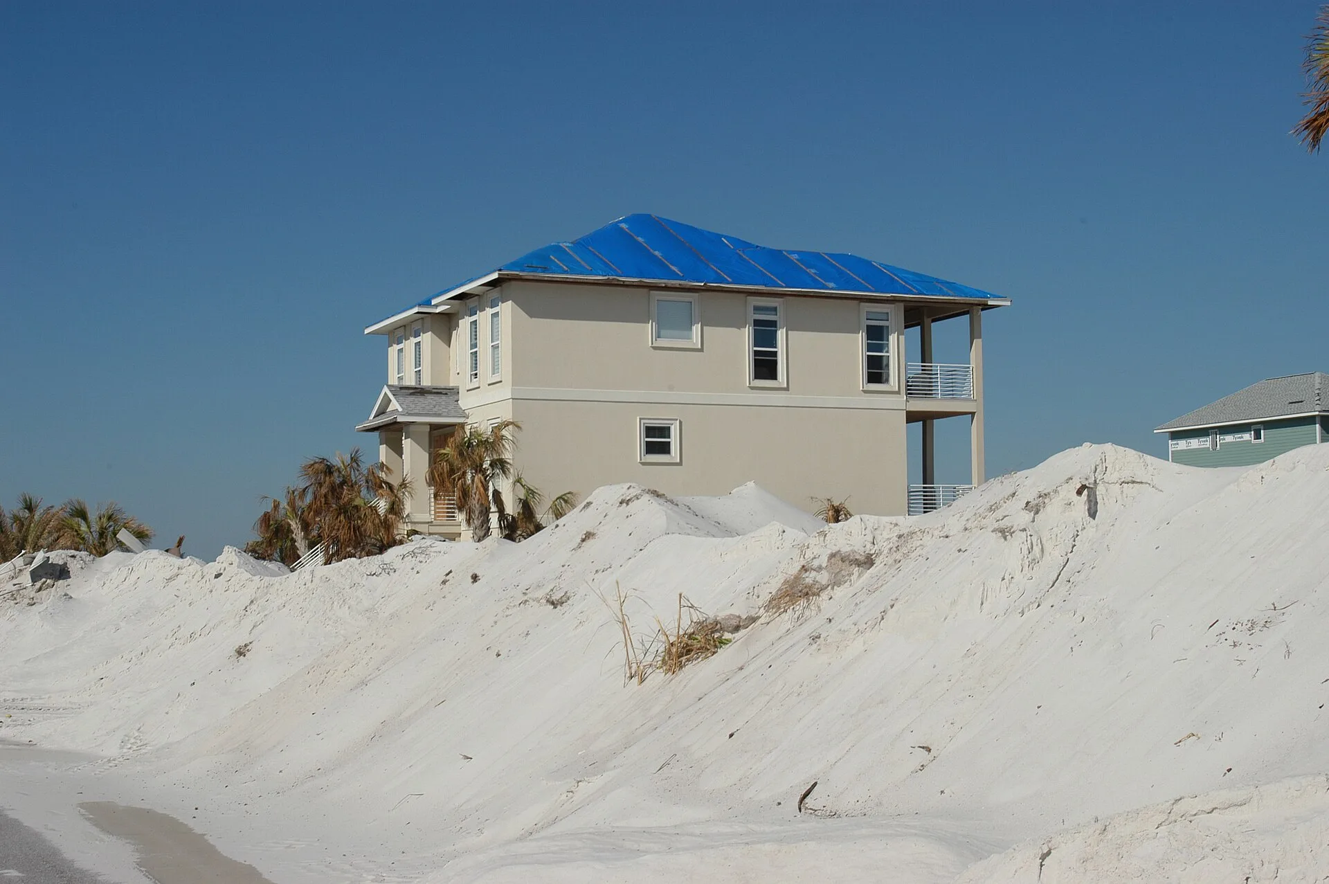 A blue tarp covers a storm-damaged roof on Pensacola Beach after Hurricane Ivan. The picture does not show Hurricane Isaias, and Pensacola Beach is not in a CRA district.