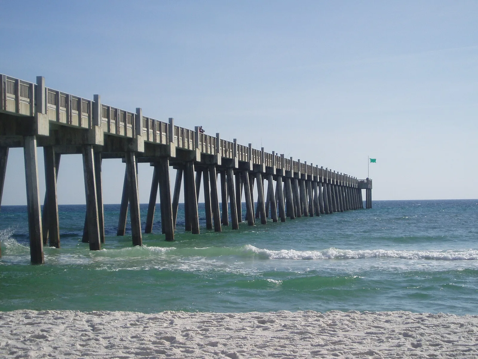The Gulf Pier stretches into the surf off the white sand of Pensacola Beach.