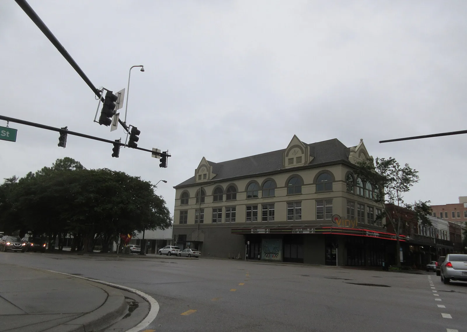 A three-story brick commercial building on a corner of Palafox Street in downtown Pensacola on a rainy day.