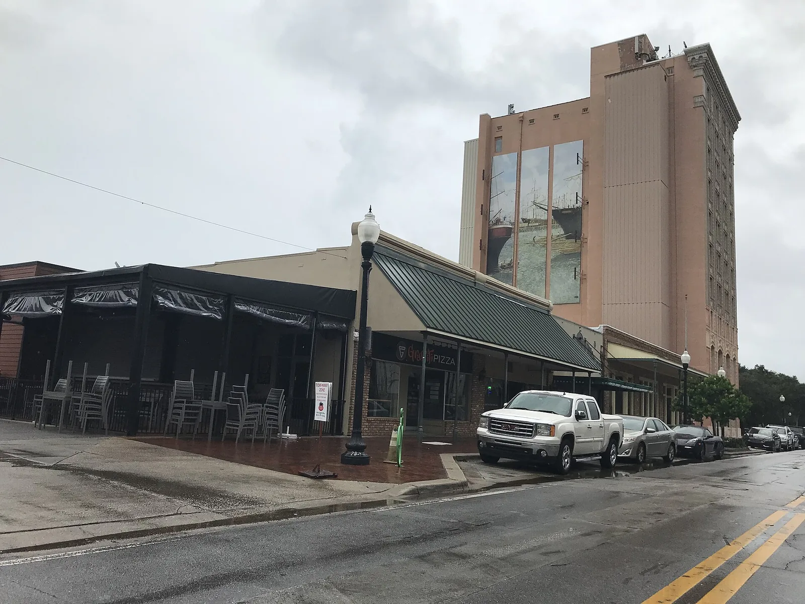 Covered outdoor seating at a restaurant corner in downtown Pensacola on a rainy day.