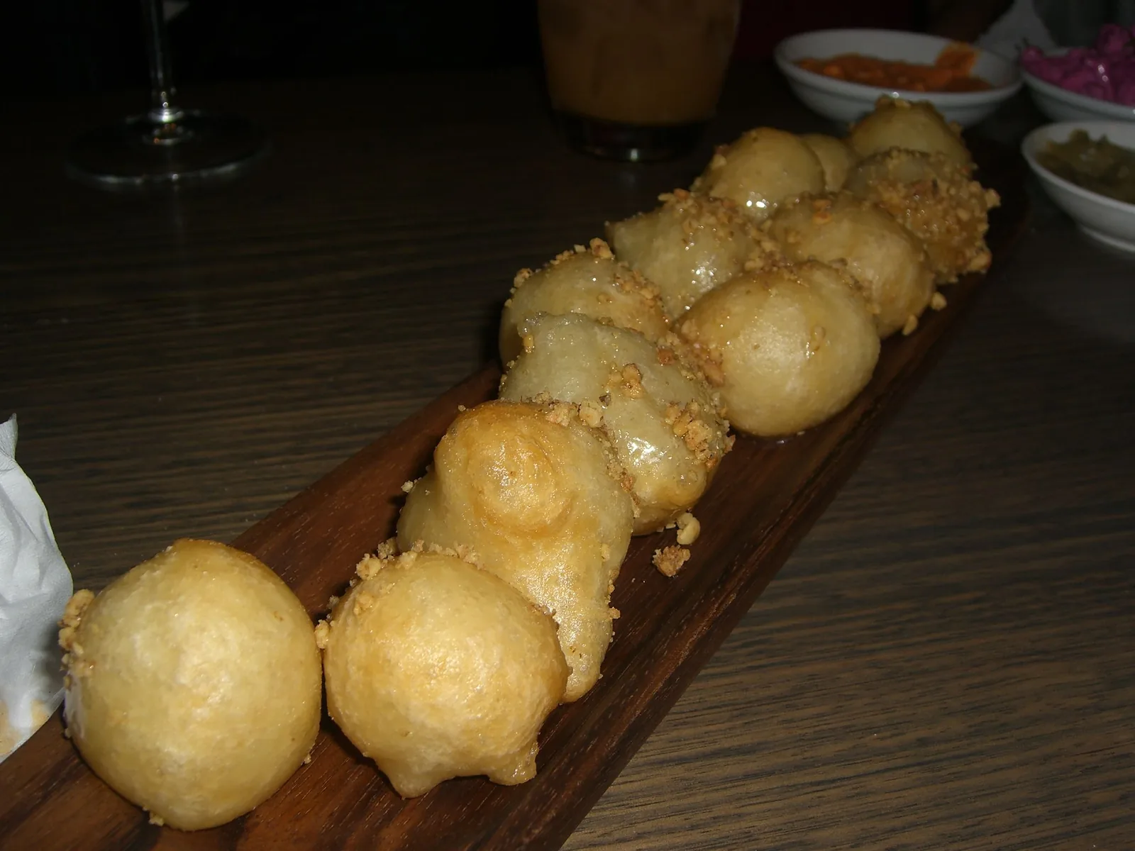 Loukoumades, Greek fried dough puffs with honey and chopped walnuts, served on a wooden board.