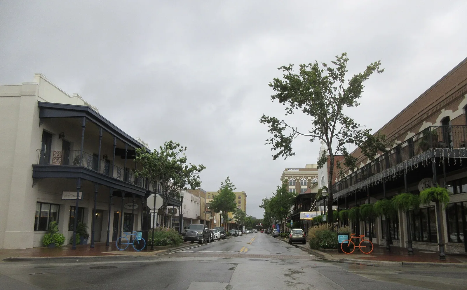 Palafox Street in downtown Pensacola, lined with balconied storefronts, on a rainy afternoon.