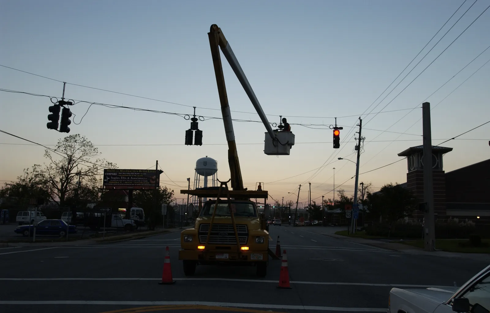 A utility crew in a bucket truck works on lines over a Pensacola intersection after Hurricane Ivan.