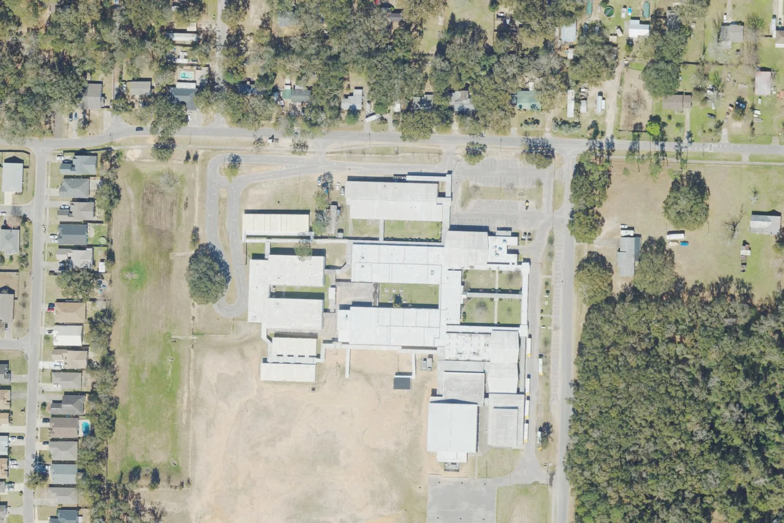 Ferry Pass Middle School's campus on Yancey Avenue north of Pensacola, between its playing field and a stand of woods, seen from the air.