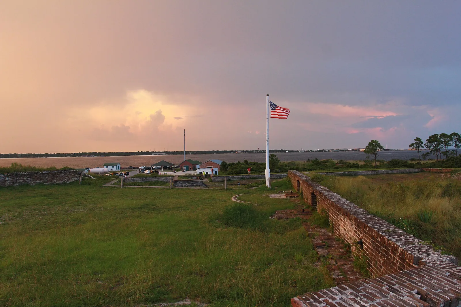 The flag flies over the walls of Fort Pickens at sunset, with Pensacola Bay beyond, at Gulf Islands National Seashore.