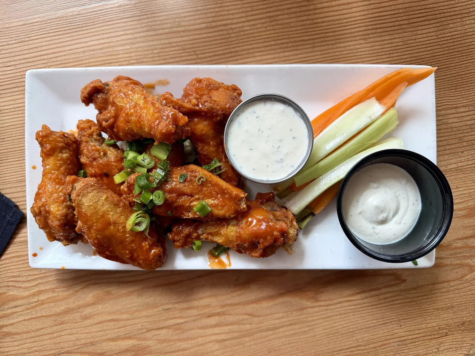 A plate of chicken wings with celery, carrots and dipping sauce at a restaurant in California, not one of the places on this list.